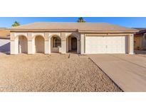 Charming single-story home featuring a two-car garage, low maintenance yard, and covered front entry with arched features at 6132 E Casper St, Mesa, AZ 85205