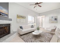 Bright living room with modern furnishings, a ceiling fan, and a cozy gray-brick fireplace at 1107 E Villa Rita Dr, Phoenix, AZ 85022