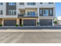 Modern townhome featuring a private balcony, dark garage doors, and clean architectural lines at 1717 E Morten Ave # 16, Phoenix, AZ 85020