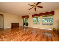 Spacious living room featuring hardwood floors, a ceiling fan, and natural light from large windows at 18400 N Deer Grass Ct, Surprise, AZ 85374