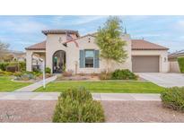 Charming home featuring a tile roof, arched entryway, manicured lawn, and an attached garage at 20618 W Western Dr, Buckeye, AZ 85396