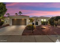 Charming single-story home with manicured landscaping and a two-car garage under a beautiful colorful sky at 22515 N Arrellaga Dr, Sun City West, AZ 85375