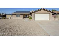 Single-story home with a gravel front yard, solar panels, brick accents and a two car garage at 3632 W Kelton Ln, Phoenix, AZ 85053