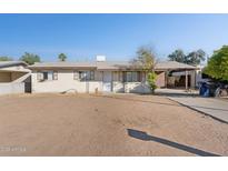 Single story home with neutral paint, decorative window coverings, dirt front yard, and covered parking at 7538 E Carol Cir, Mesa, AZ 85208