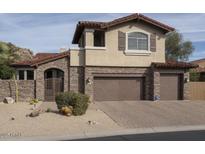 Two-story home boasts a stone facade, two-car garage, desert landscaping, and a red tile roof at 7546 E Camino Puesta Del Sol --, Scottsdale, AZ 85266