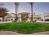Elegant home featuring manicured lawn, palm trees, and a circular driveway leading to a covered entrance at 9128 N 70Th St, Paradise Valley, AZ 85253