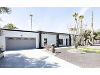 Charming single-story home featuring a landscaped front yard, desert foliage, and modern architectural details at 6621 E Sharon Dr, Scottsdale, AZ 85254