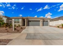 Charming home exterior with a stone facade, neutral color palette, and a spacious three-car garage at 18434 W Chama Dr, Surprise, AZ 85387