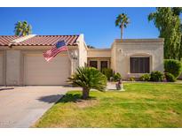 Charming home exterior with a well-manicured lawn, an American flag, and desert landscaping at 19093 N 97Th Ln, Peoria, AZ 85382