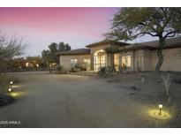 Inviting desert home with stone accents, mature landscaping, and private drive at dusk at 25409 N Ranch Gate Rd, Scottsdale, AZ 85255