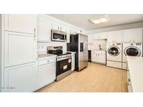 Modern kitchen with stainless steel appliances and white cabinets, including a washer and dryer at 726 N 78Th St, Scottsdale, AZ 85257