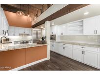 Bright kitchen with white cabinets, stone countertops, stainless steel appliances, and unique light fixtures at 8502 E Cave Creek Rd # 53, Carefree, AZ 85377