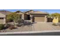 Charming home with stone facade, desert landscaping, tiled roof, and inviting two-car garage at 8634 E Kael Cir, Mesa, AZ 85207