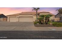 Charming single-story home featuring a three-car garage, desert landscaping, and a clay tile roof at sunset at 9544 E Irwin Ave, Mesa, AZ 85209