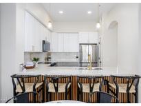 Bright kitchen with stainless steel appliances, white cabinetry and a stylish island with barstool seating at 11000 N 77Th Pl # 2032, Scottsdale, AZ 85260