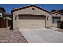 A tan two-car garage with a driveway and stone landscaping with matching trim details and beige siding at 13226 W Fairmont Ave, Litchfield Park, AZ 85340