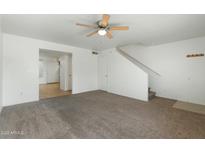 Bright living room with neutral carpet, ceiling fan, and staircase to the upper level at 18239 N 40Th St # 107, Phoenix, AZ 85032
