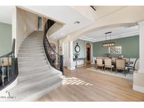 Open foyer with a curved staircase, wood floors, and elegant dining area, creating an inviting space at 6960 E Ivyglen St, Mesa, AZ 85207