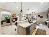 Elegant kitchen featuring an island with a sink, pendant lighting, and an adjoining dining area at 6960 E Ivyglen St, Mesa, AZ 85207