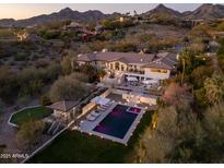 Stunning aerial view of a luxury home with pool, lush landscaping, and mountain backdrop at dusk at 3977 E Paradise View Dr, Paradise Valley, AZ 85253