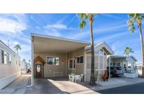 Charming home featuring covered parking, a cozy seating area, and lush palm trees against a bright blue sky at 834/837 S Beryl/Aquamarine Dr, Apache Junction, AZ 85119