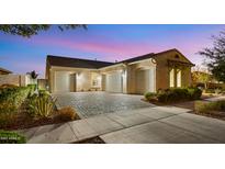 Charming home exterior featuring a three-car garage and desert landscaping at twilight at 10455 E Thatcher Ave, Mesa, AZ 85212