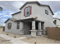 Two-story home featuring a covered porch with brick supports and decorative shutters at 14650 W Sand Hills Rd, Surprise, AZ 85387