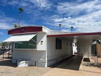 Cozy mobile home featuring white siding, red trim, awning, and carport for convenient parking at 4065 E University Dr # 271, Mesa, AZ 85205