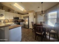 Bright kitchen with a dining area, skylight, white cabinetry, stainless steel appliances and tiled floors at 650 N Hawes Rd # 4834, Mesa, AZ 85207
