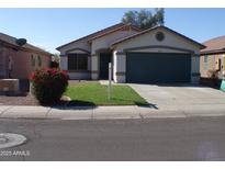Charming single-Gathering home featuring a two-car garage and a well-maintained front yard with green grass and a decorative bush at 13819 W Berridge Ln, Litchfield Park, AZ 85340