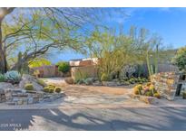 A desert landscape welcomes you to this home with mature trees, cacti, and stone accents, with a circular driveway at 34460 N 79Th Way, Scottsdale, AZ 85266
