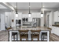 Modern kitchen with white cabinets, granite countertops, stainless steel appliances, and three pendant lights at 3930 E Enrose St, Mesa, AZ 85205