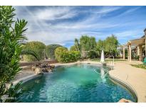 Beautiful backyard pool with rock waterfall feature and lush landscaping in a private setting at 15109 W Camino Estrella Dr, Surprise, AZ 85374