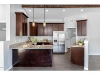 Modern kitchen featuring dark wood cabinets, granite countertops, stainless steel appliances, and stylish pendant lighting at 16414 N Dixie Mine Trl, Fountain Hills, AZ 85268