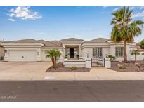 Stunning white home featuring a well-kept landscape, tile roof, three car garage, and a decorative front gate at 5323 W Rose Garden Ln, Glendale, AZ 85308
