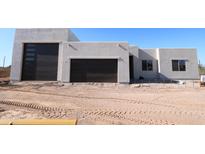 Modern home exterior featuring a stucco facade, dark garage doors, and desert landscaping at 29022 N 166Th Ave, Surprise, AZ 85387