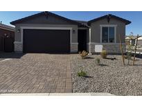 Charming single-story home featuring a brick-paved driveway, low-maintenance landscaping, and a two-car garage at 39966 W Anne Ln, Maricopa, AZ 85138