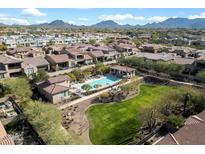 Stunning aerial view of the community pool, green space, and surrounding homes, all with a mountain view in the background at 7340 E Conquistadores Dr, Scottsdale, AZ 85255