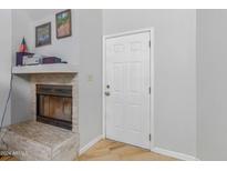Bright living room with a white door and a cozy fireplace featuring a stone facade and a decorative mantel at 16402 N 31St St # 228, Phoenix, AZ 85032