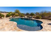 Inviting backyard pool features flagstone deck, accent wall, and black metal safety fence at 27621 N 174Th Dr, Surprise, AZ 85387