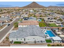 Expansive aerial view of a planned community, mountain backdrop, and a backyard featuring a modern pool and playground at 31489 N 126Th Ln, Peoria, AZ 85383