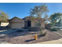Charming single-story home showcasing desert landscaping, a two-car garage, and light tan stucco at 4943 W Lynne Ln, Laveen, AZ 85339