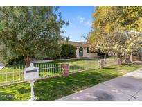 Charming single-story home with a well-manicured lawn, mature trees, and white picket fence at 5144 N 69Th Pl, Paradise Valley, AZ 85253
