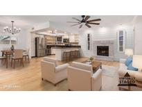 Bright, open-concept living room featuring hardwood floors, fireplace, and kitchen island with bar seating at 8201 W Tuckey Ln, Glendale, AZ 85303