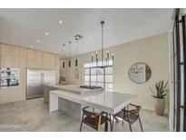 Bright kitchen with island cooktop, modern lighting, light wood cabinets, and stainless steel appliances at 14132 W Bent Tree S Cir, Litchfield Park, AZ 85340