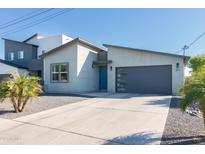 Modern home exterior with a gray garage door, blue front door, and desert landscaping at 2819 N 28Th Pl, Phoenix, AZ 85008