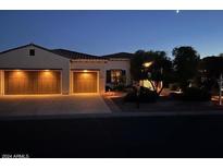 Charming home exterior illuminated at night, showcasing a two-car garage and manicured landscaping at 13117 W Micheltorena Dr, Sun City West, AZ 85375