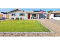 Charming home featuring a well-manicured lawn, a bright red front door, and solar panels for energy efficiency at 2008 E Mitchell Dr, Phoenix, AZ 85016