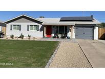 Charming home with a well-manicured front yard, solar panels, a vibrant red door, and stylish gray garage at 2008 E Mitchell Dr, Phoenix, AZ 85016