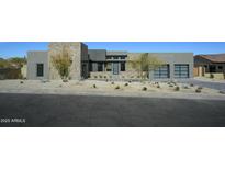 Contemporary home's exterior shows natural stone accents, desert landscaping, and a modern design at 12856 E Rosewood Dr, Scottsdale, AZ 85255